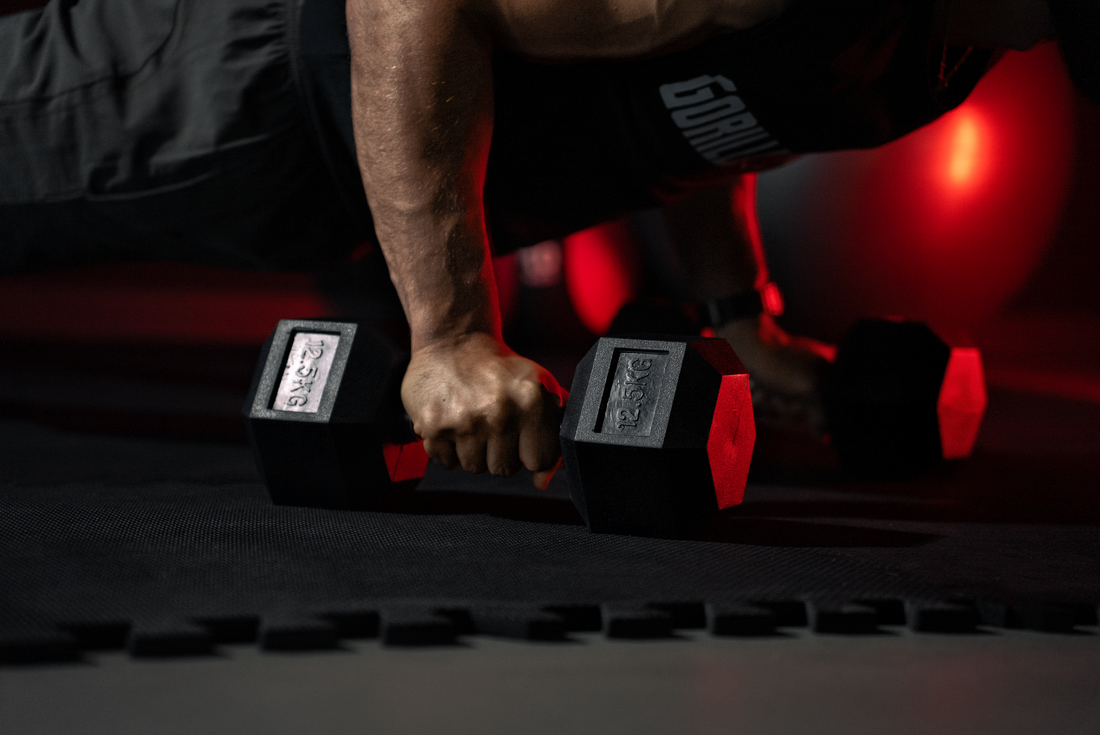 Person macht Liegestütze mit Kurzhanteln auf einer Trainingsmatte